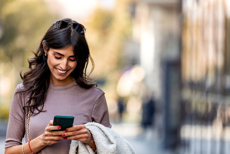 Una mujer mira su smartphone con una sonrisa